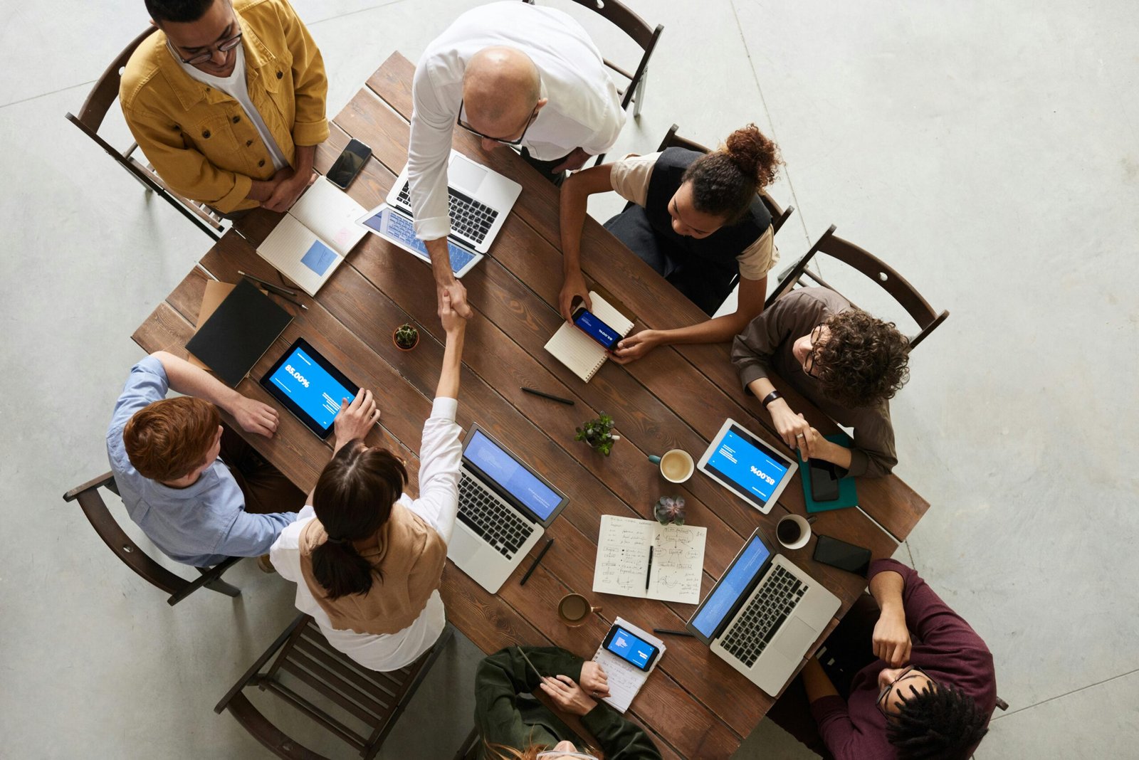 Services Top view of a diverse team collaborating in an office setting with laptops and tablets, promoting cooperation.